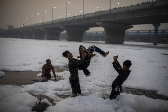 Polluted air and water: Young Hindu devotees play in the Yamuna river, covered by chemical foam from ndustrial and domestic pollution, during Chhath Puja festival in New Delhi on Wednesday.
