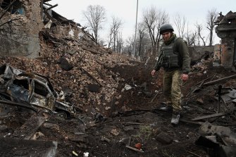 A Ukrainian soldier stands at the edge of an eight-metre crater where people once lived. 