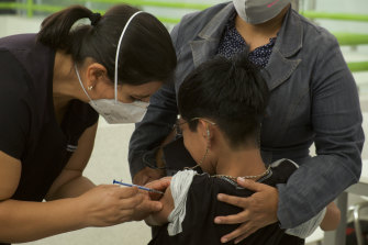 A healthcare worker injects a boy with a dose of the Pfizer COVID-19 vaccine in Mexico.