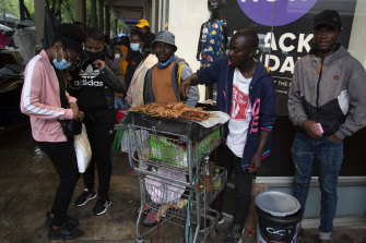 A woman wearing a face mask to curb the spread of coronavirus buys chicken on a crowded footpath in Pretoria, South Africa.