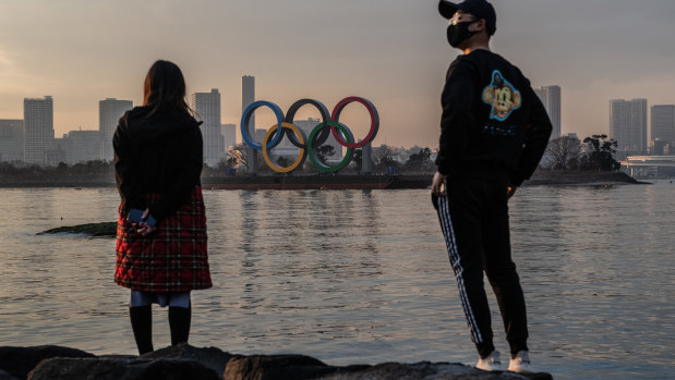  A woman and a  man wearing a face mask view the Olympic Rings on January 22, 2021 in Tokyo, Japan. 
