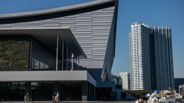 Construction workers push carts past the Ariake Arena, which will host Volleyball during the 2020 Olympics in Tokyo, Japan. 