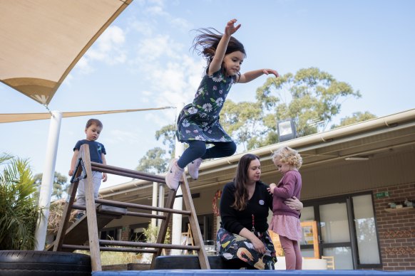 Preschooler Mila makes a leap with friends Eddy and Olena, and teacher Angela Aldridge, at Goodstart’s Crescent Early Learning Centre. 