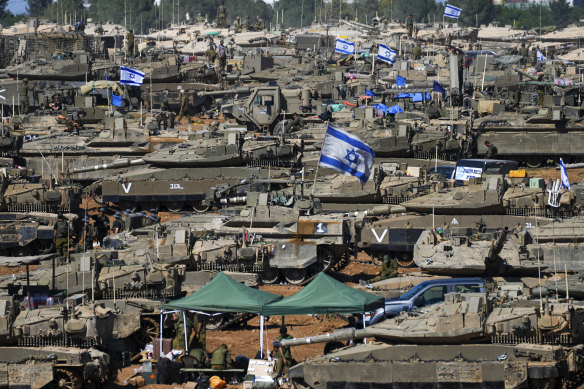 Israeli soldiers work on armored military vehicles at a staging ground near the Israeli-Gaza border.