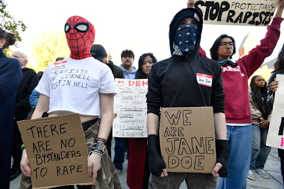 Demonstrators hold signs during a protest against the university’s handling of gang rape allegations.