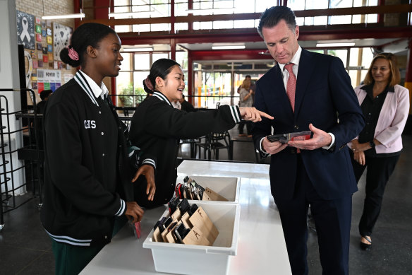 Chris Minns learns how to check in a phone during a visit to Condell Park High School, where a ban is already in place.