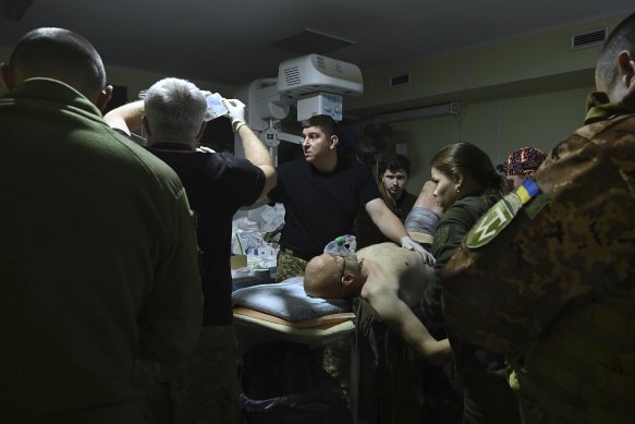 Head co-ordinating doctor and surgeon Serhiy, 41, (3rd from left) treats a wounded Ukrainian soldier with shrapnel wounds.
