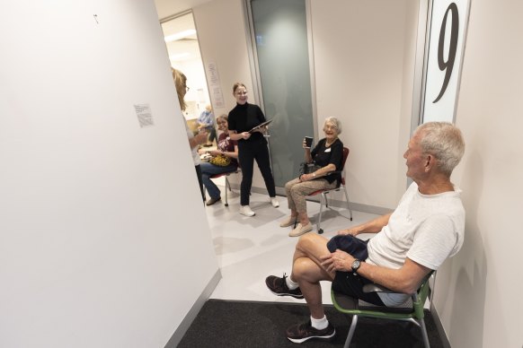 John Seitz and Heather Griffiths sit in a waiting area after receiving the AstraZeneca vaccine at a vaccination centre in Olympic Park.