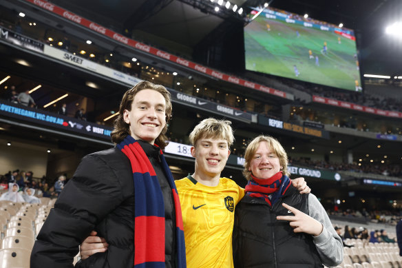 Every heart beats true: Demons supporters bookend a Matildas fan on a historic day at the MCG.