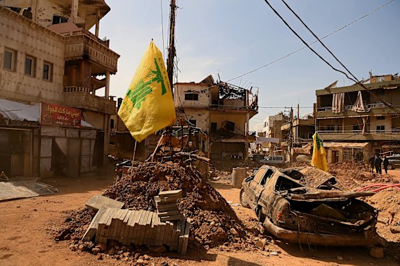 A bombed car in the town in the aftermath of the attack, a Hezbollah flag flying above it.