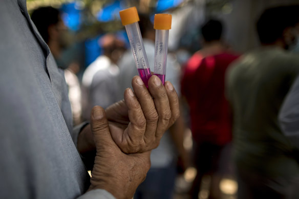 A man waits with his sample at a Covid-19 testing station in New Delhi, India, on Friday.