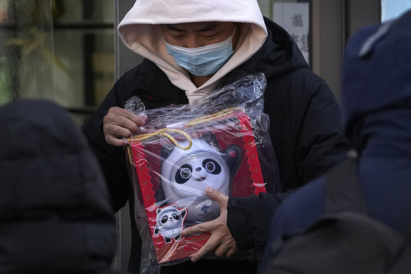 A man holds the Olympic mascot Bing Dwen Dwen doll purchased from a store selling 2022 Winter Olympics merchandise in Beijing on Monday.