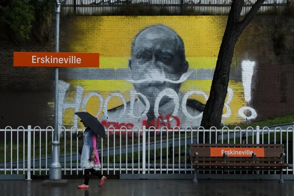 A woman stands near a mural at Erskineville station depicting former RFS chief Shane Fitzsimmons  that has been graffitied for a second time.