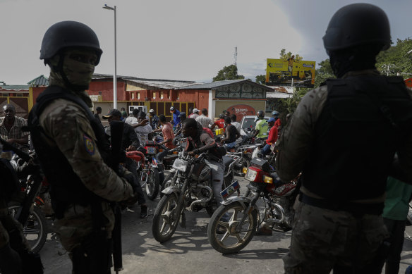 Police officers wait to have their truck filled with petrol at one of the few open service stations in the Haitian capital.