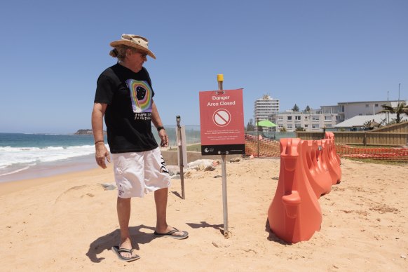 Surfrider Foundation Australia northern beaches president Brendan Donohoe stands next to a warning sign at Collaroy Beach.