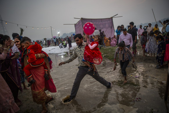 An Indian Hindu family crosses the shallow banks of the Yamuna river during Chhath Puja festival in New Delhi, India. During Chhath, an ancient Hindu festival, rituals are performed to thank the sun god for sustaining life on earth.