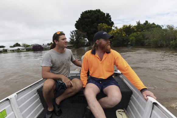 Grafton residents and mates Dave O’Cass and Zac Walsh search for Mr O’Cass’ boat, which broke free from its mooring in floodwaters overnight.