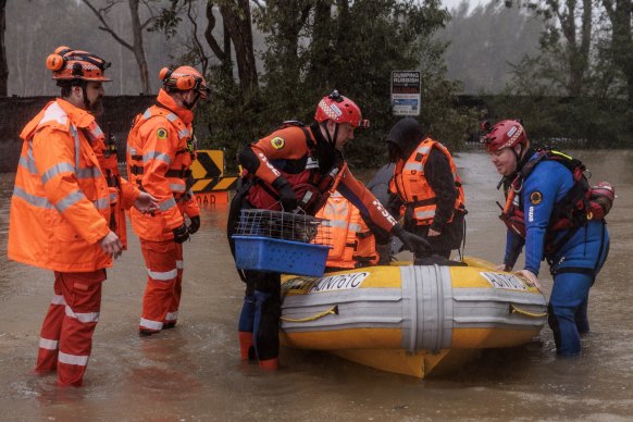 Lansvale residents Jack and Jamarcus, along with their pets, are evacuated by the NSW SES Kogarah Unit as flood waters rise along the Georges River on Sunday.