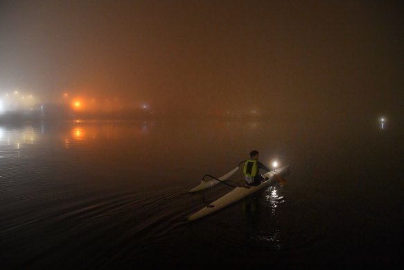 Ian Ong in his outrigger canoe in Rozelle Bay under a blanket of fog at Federal Park in Annandale. 