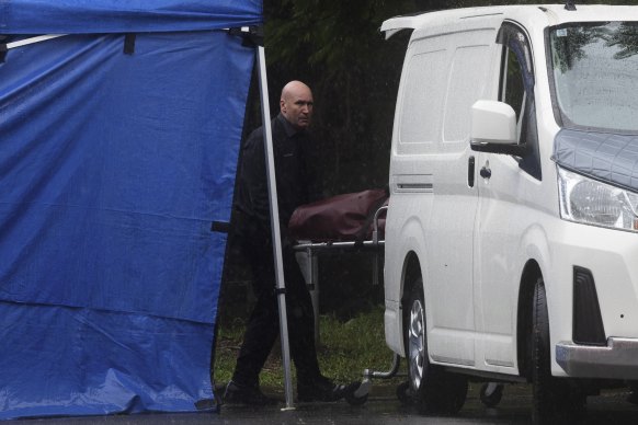 A body is loaded into a waiting van at the scene on Tuesday. 