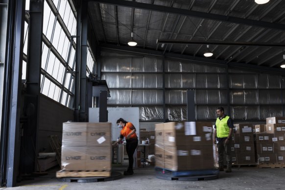 Sandira Sami and Sherif Abdelmalak pack boxes of rapid antigen tests at a warehouse in Sydney’s west.