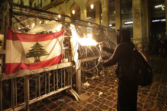 A protester uses an aerosol can to blast fire at police in Lebanon's capital.