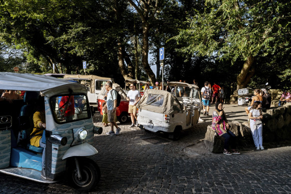 Tuktuks drop off and pick up tourists at the gate of the 19th century Pena Palace in Sintra, Portugal.