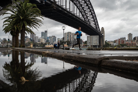 A jogger runs beneath the Sydney Harbour Bridge on a rainy Saturday morning.
