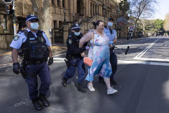 An anti-lockdown protester is arrested and detained outside NSW state parliament. 