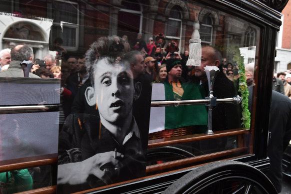 Crowds of people follow MacGowan’s funeral procession in Dublin.