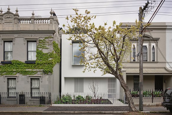 The sleek and minimal contemporary house is framed by two ornate Victorian terraces on either side.