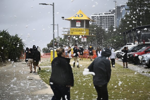 Locals enjoy flying sea foam generated by strong winds at Main Beach.