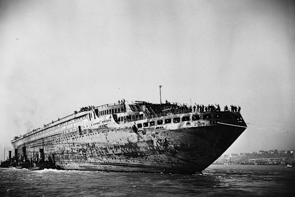 The remains of the Normandie were tugged to Brooklyn Naval Yard – she was sold as scrap in 1946.