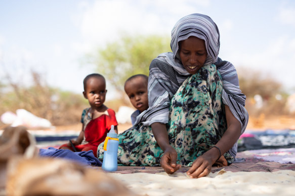 Mother-of-four Nimo Ibrahim sews pieces of old cloth into a tarpaulin to drape over the roof of her hut at a camp for displaced people in Somaliland.