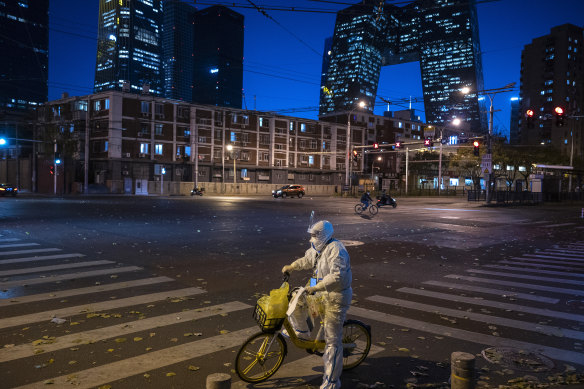 An epidemic control worker who performs nucleic acid tests on people  stops to check a list on a usually busy street during rush hour on Friday.