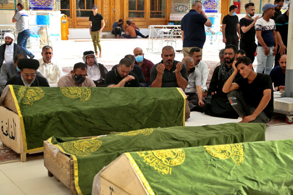 Mourners pray near the coffins of coronavirus patients who were killed in a hospital fire, in Najaf, Iraq.