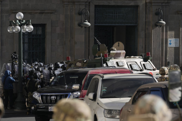 Poliția militară se adună în fața intrării principale în timp ce un vehicul blindat sparge ușa palatului prezidențial din Plaza Murillo din La Paz, Bolivia.