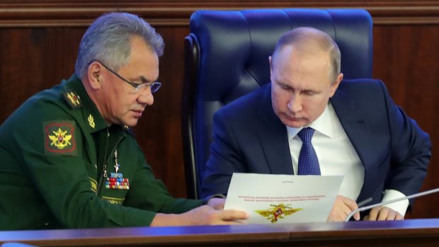 Russian President Vladimir Putin, right, and Defence Minister Sergey Shoigu talk to each other after visiting an exhibition at the Russian military's headquarters as part of a conference on the Russian campaign in Syria.