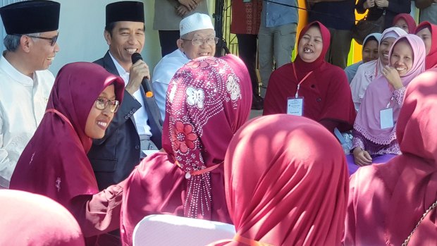 Joko Widodo addresses residents in the town of Serang, in Banten province, accompanied by the chairman of the Financial Services Authority, Wimboh Santoso, and the head of the Indonesian Ulema Council, Ma'ruf Amin.  