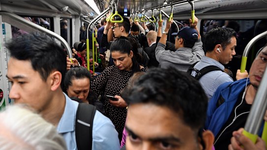 Commuters pack a city-bound metro train during the morning peak.