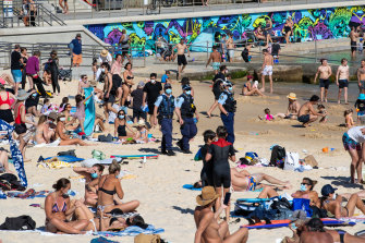 Masked police amid the unmasked crowds on Bondi Beach last Sunday.
