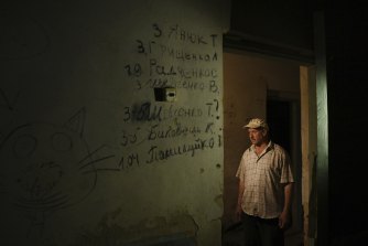 62 yaşındaki Ivan, neredeyse 371 kişilik köyün tamamının tutulduğu Yahidne'deki bir okulun bodrum katının kapısında duruyor.  Duvardaki yedi isim ölenlerden.