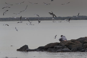 A family member sits at the water’s edge.