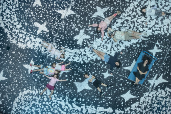 Kids lie on the stunning floor mural made from Naminapu Maymuru-White’s 
Milŋiyawuy  or River of stars at the NGV, as part of the Bark Ladies exhibition. 