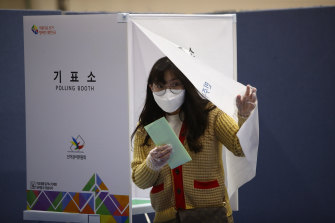 A South Korean woman wears a mask and plastic gloves while casting her vote in Seoul.