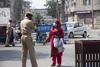 A Kashmiri woman requests a police officer to let her cross a street during curfew in Srinagar, Indian controlled Kashmir, on Tuesday.