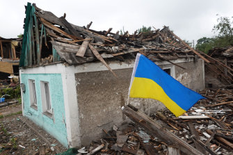 Una bandiera ucraina sventola accanto a una casa gravemente danneggiata da un attacco missilistico russo il 15 giugno 2022 a Dopropylya, nell'Ucraina orientale. 