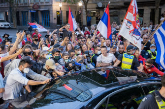 Fans mob a car as it leaves the offices of Novak Djokovic’s lawyers on Monday night. 