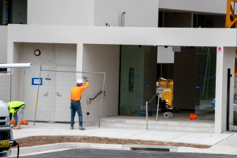Workers shift temporary fences at the apartment building on Friday.
