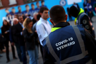 A COVID-19 steward monitors the crowds before a UEFA Champions League match in London last week.